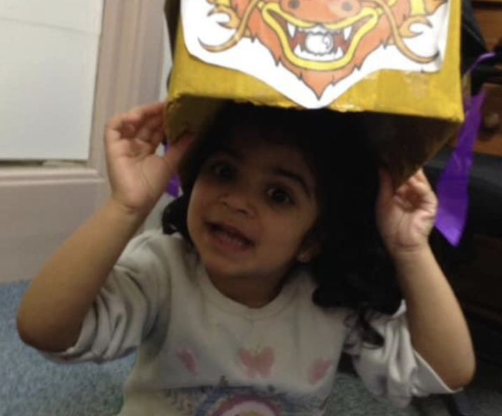 A child wearing a handmade dragon mask at the nursery